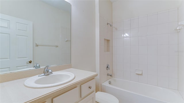 full bathroom with tiled shower / bath, vanity, and toilet