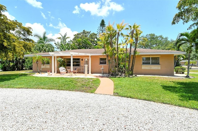 ranch-style home with a front yard and a patio area