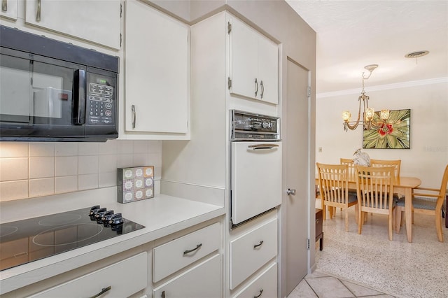 kitchen with tasteful backsplash, white cabinets, hanging light fixtures, ornamental molding, and black appliances