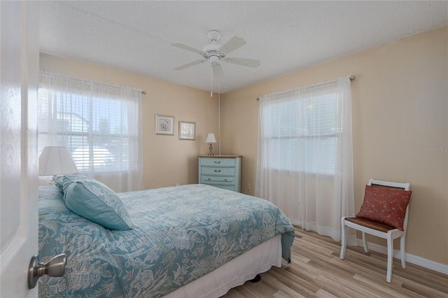 bedroom with ceiling fan, a textured ceiling, and light wood-type flooring