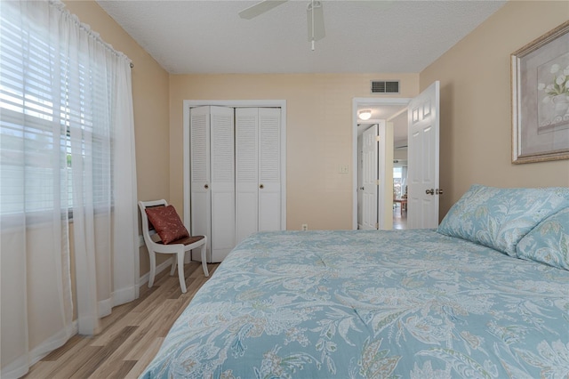 bedroom with ceiling fan, a closet, a textured ceiling, and light hardwood / wood-style floors