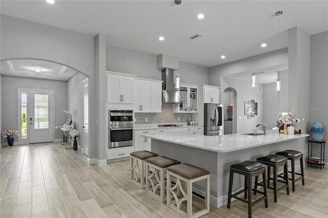 kitchen with appliances with stainless steel finishes, decorative light fixtures, and wall chimney exhaust hood