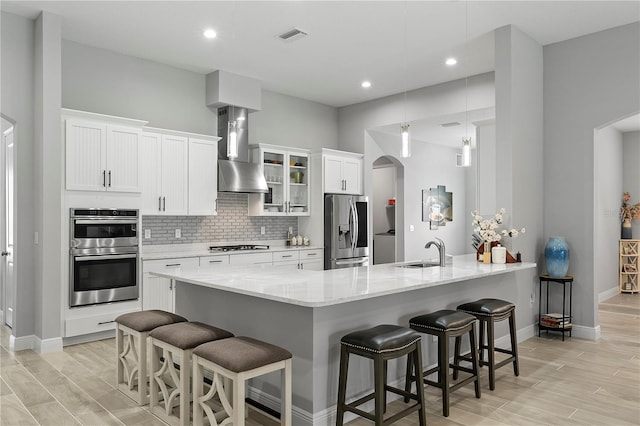 kitchen with light hardwood / wood-style floors, kitchen peninsula, stainless steel appliances, backsplash, and hanging light fixtures