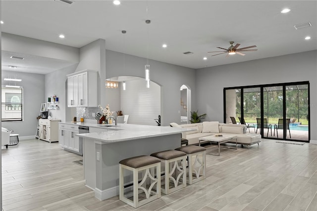 kitchen featuring backsplash, hanging light fixtures, white cabinets, and a breakfast bar area