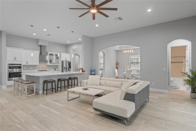 living room with ceiling fan with notable chandelier