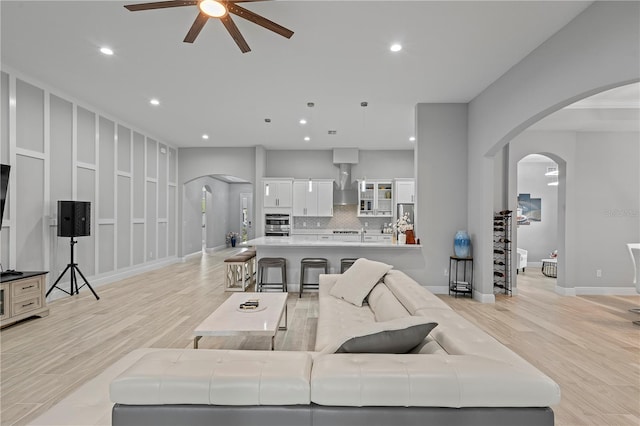 living room with sink, light wood-type flooring, and ceiling fan