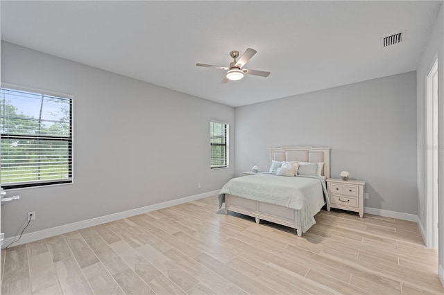 bedroom with ceiling fan, multiple windows, and light hardwood / wood-style flooring