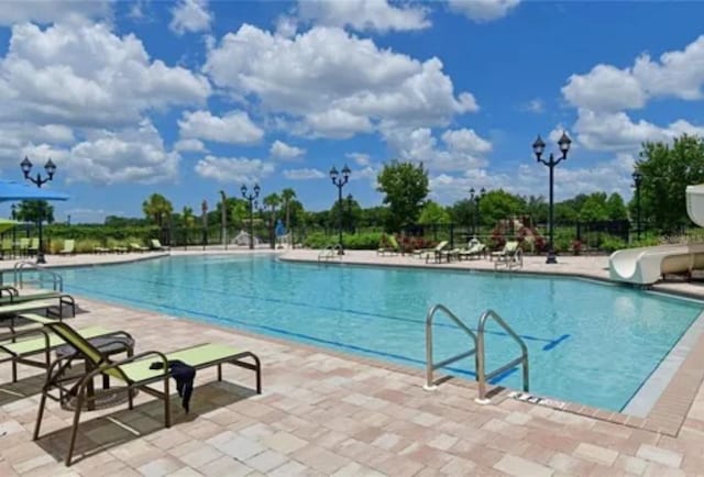 view of swimming pool with a patio area and a water slide