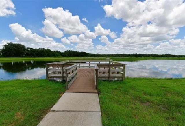 view of dock with a water view and a yard