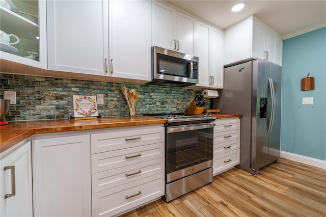 kitchen featuring stainless steel appliances, white cabinetry, tasteful backsplash, and butcher block counters