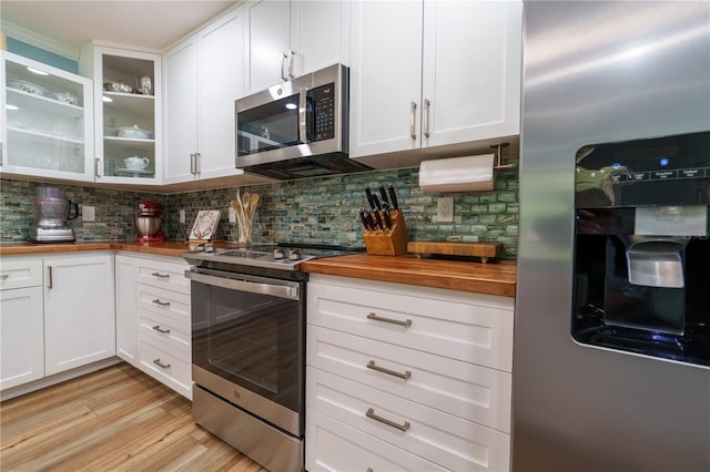 kitchen with butcher block countertops, white cabinets, stainless steel appliances, and tasteful backsplash