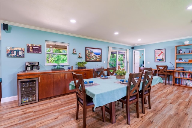 dining space featuring a wealth of natural light, light hardwood / wood-style floors, beverage cooler, and ornamental molding