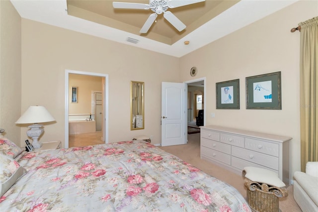 carpeted bedroom featuring ceiling fan, connected bathroom, and a tray ceiling