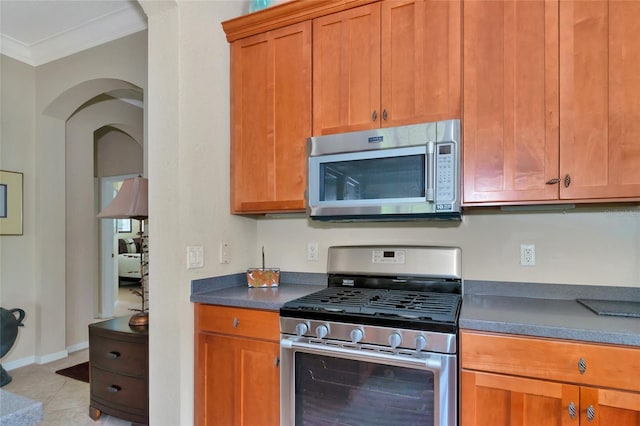 kitchen featuring appliances with stainless steel finishes, crown molding, and light tile floors