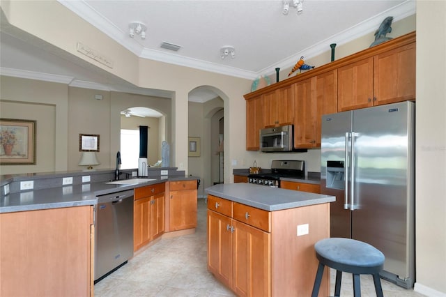 kitchen featuring stainless steel appliances, light tile flooring, a kitchen island, sink, and ornamental molding