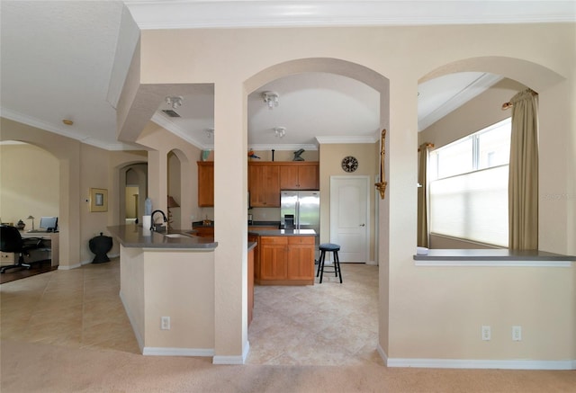 kitchen with crown molding, stainless steel fridge, kitchen peninsula, sink, and light tile floors