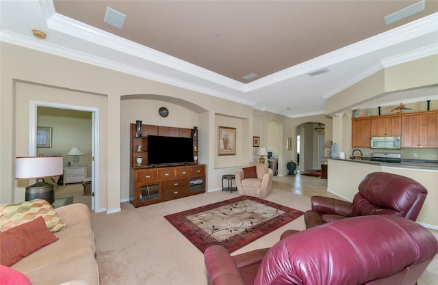 carpeted living room with a raised ceiling and ornamental molding