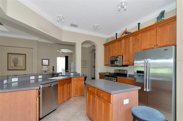 kitchen with ornamental molding, light tile flooring, a kitchen island, and appliances with stainless steel finishes