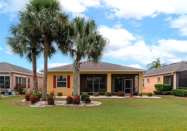 rear view of house with a yard and a sunroom