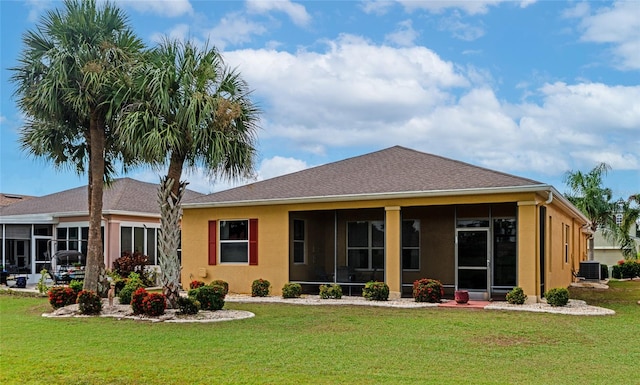 rear view of house with central AC unit and a lawn