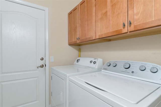 washroom with washer and dryer and cabinets