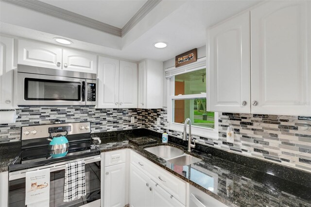 kitchen with white cabinets, appliances with stainless steel finishes, and dark stone countertops