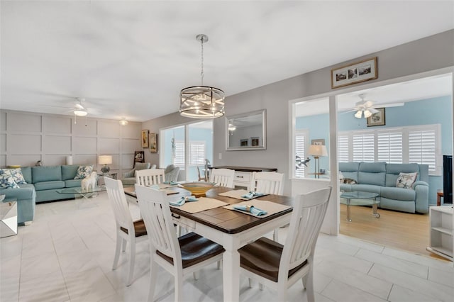 tiled dining area with ceiling fan with notable chandelier