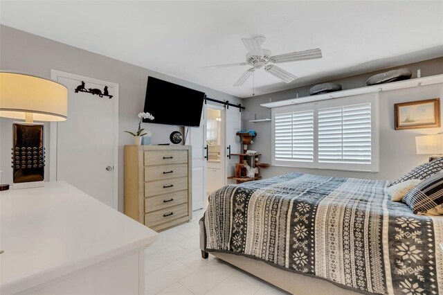 bedroom featuring connected bathroom, ceiling fan, and a barn door