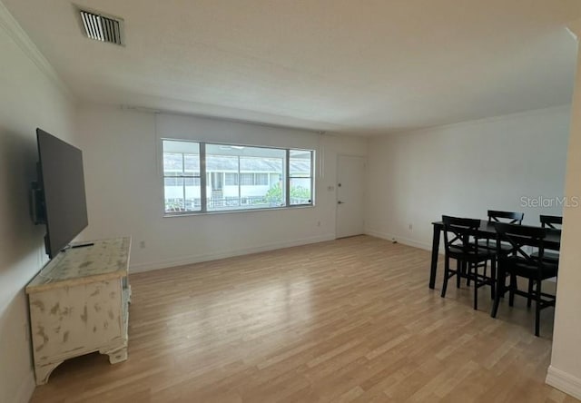 dining space with crown molding and light hardwood / wood-style floors