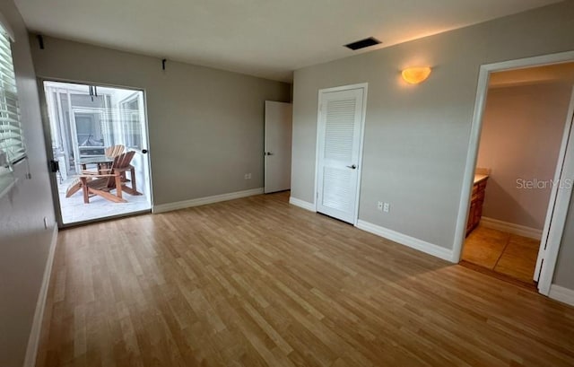 unfurnished bedroom featuring ensuite bath and light hardwood / wood-style flooring