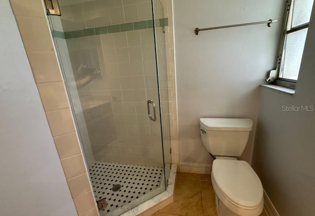 bathroom featuring tile patterned floors, a shower with shower door, and toilet