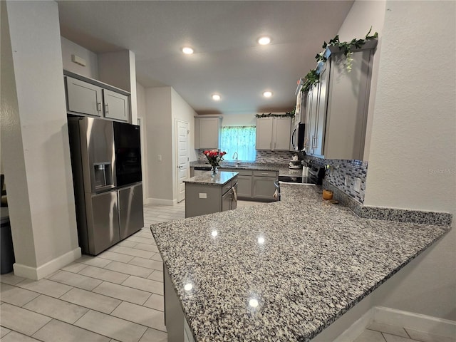 kitchen featuring sink, appliances with stainless steel finishes, gray cabinetry, dark stone countertops, and a kitchen island