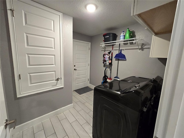 laundry room featuring cabinets, washer and dryer, and a textured ceiling