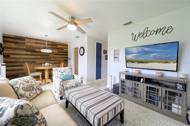 living room featuring ceiling fan and wooden walls