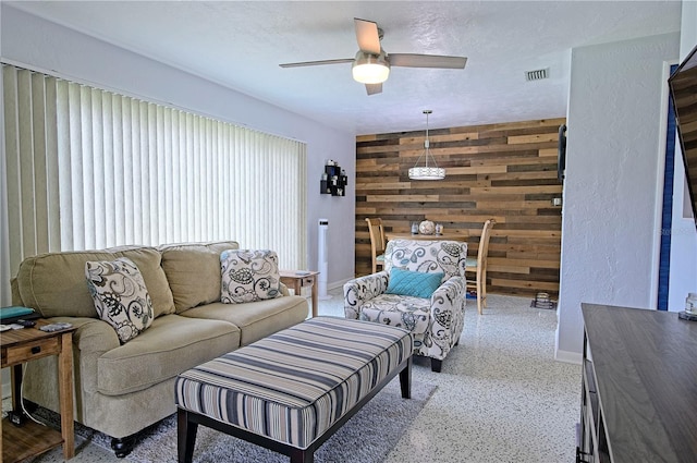 living room featuring wood walls and ceiling fan