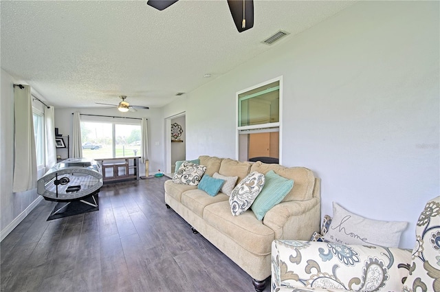 living room featuring ceiling fan, dark hardwood / wood-style flooring, and a textured ceiling