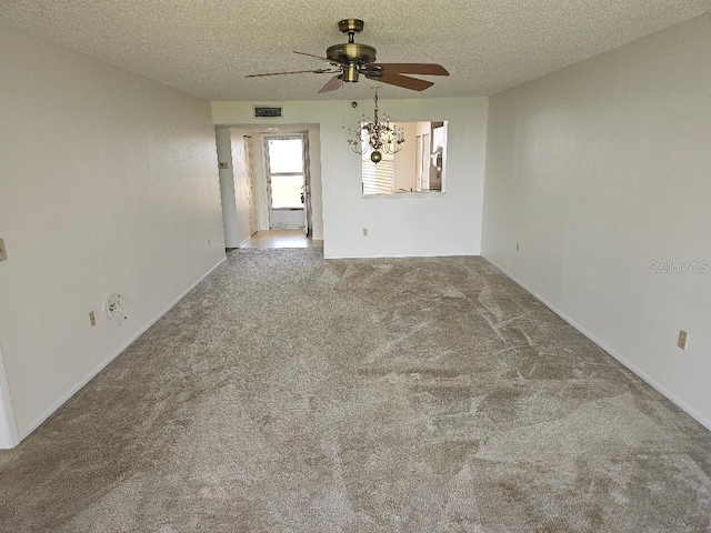 empty room featuring ceiling fan with notable chandelier, a textured ceiling, and carpet floors