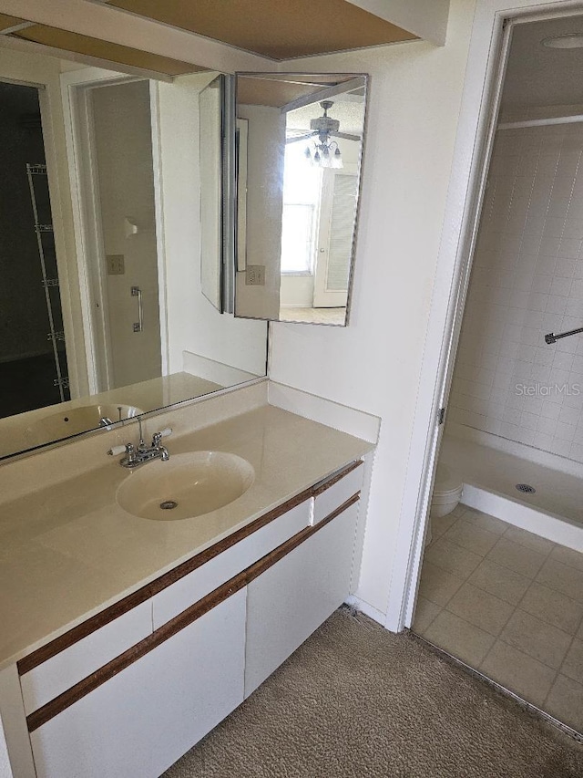 bathroom with tiled shower, toilet, tile patterned floors, and vanity