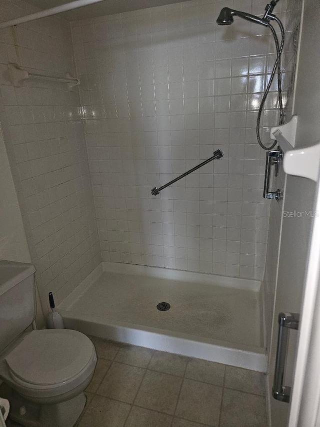 bathroom with a tile shower, tile patterned flooring, and toilet