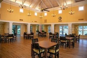 dining area with a towering ceiling, a notable chandelier, decorative columns, and wood-type flooring