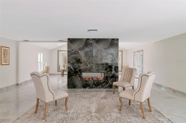 sitting room with lofted ceiling and a tiled fireplace