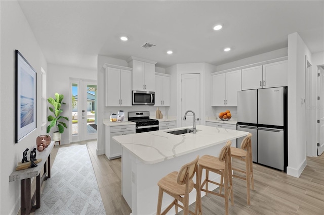 kitchen with white cabinets, appliances with stainless steel finishes, light hardwood / wood-style floors, and sink