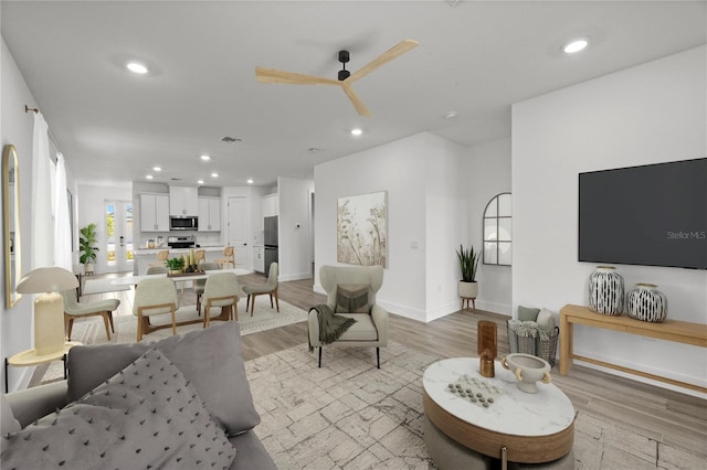 living room with ceiling fan and light hardwood / wood-style flooring