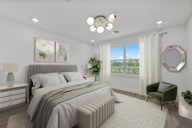 bedroom featuring wood-type flooring and an inviting chandelier