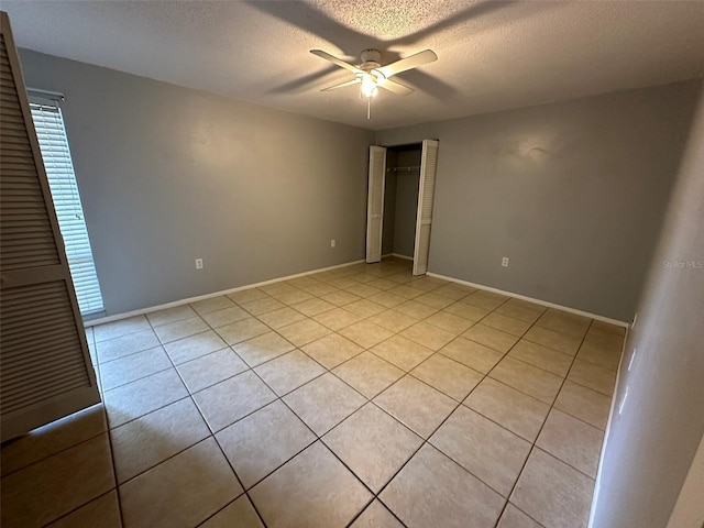 unfurnished bedroom featuring ceiling fan, a textured ceiling, and light tile patterned floors