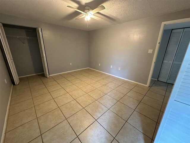 unfurnished bedroom with light tile patterned floors, a textured ceiling, ceiling fan, and a closet