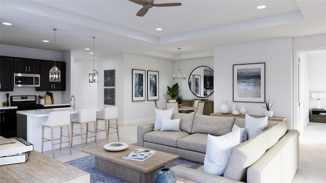 tiled living room featuring ceiling fan with notable chandelier and a raised ceiling