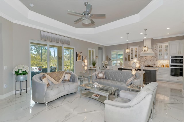 living room featuring ceiling fan, crown molding, a wealth of natural light, and a tray ceiling