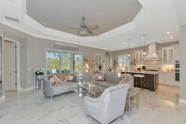 living room featuring a raised ceiling, crown molding, plenty of natural light, and ceiling fan