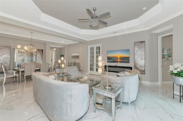 living room with a tray ceiling, french doors, ceiling fan with notable chandelier, and ornamental molding